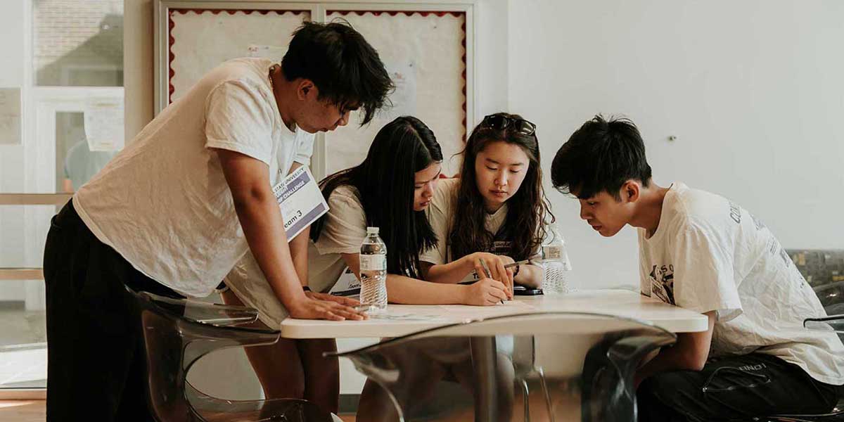 A group of students sit around a table to answer trivia questions